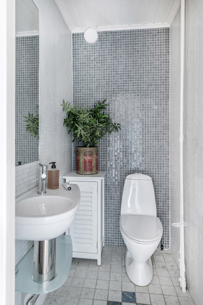 Design ideas for a small scandinavian powder room in Stockholm with a one-piece toilet, gray tile, mosaic tile, grey walls, a wall-mount sink and multi-coloured floor.