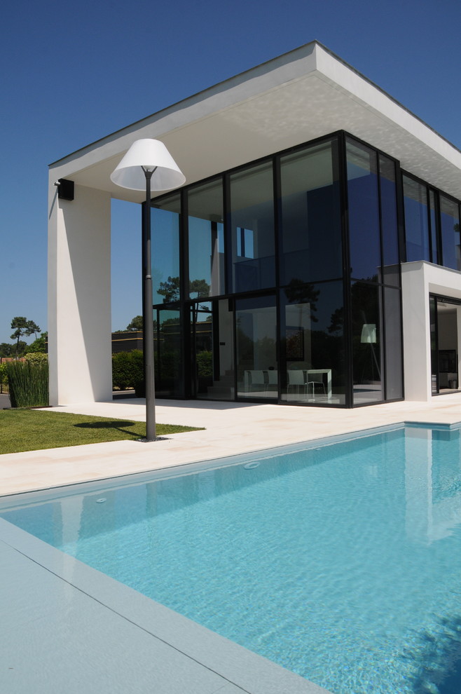 Photo of a large contemporary two-storey glass white exterior in Marseille with a flat roof.