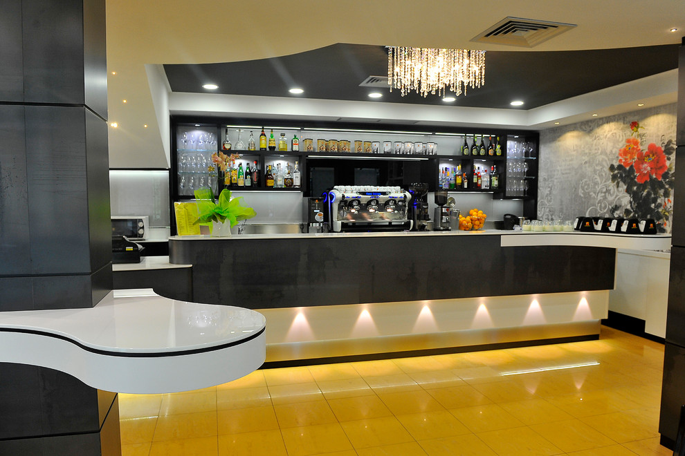 This is an example of a modern home bar in Miami with glass benchtops and yellow splashback.