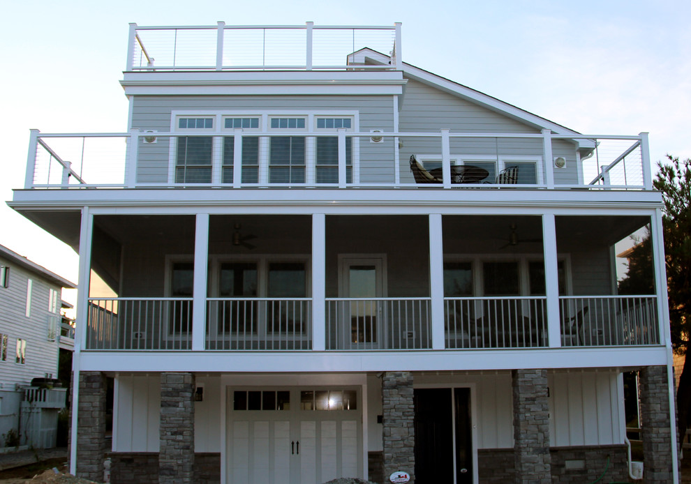 This is an example of a large beach style three-storey grey exterior in Other with concrete fiberboard siding.