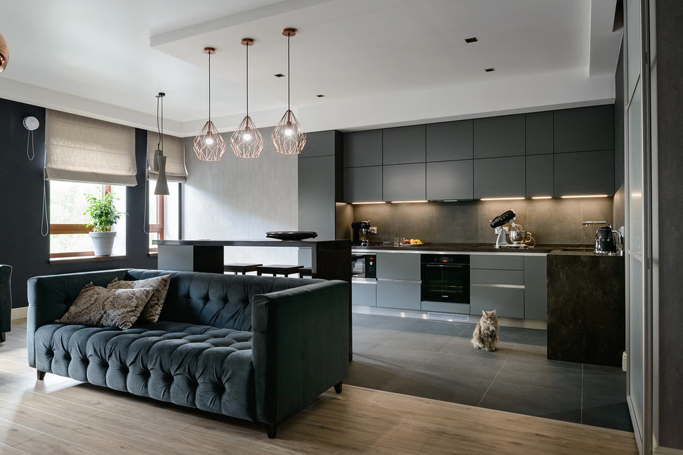 Design ideas for a mid-sized contemporary l-shaped open plan kitchen in Other with grey cabinets, solid surface benchtops, porcelain splashback, porcelain floors, grey floor, grey benchtop, flat-panel cabinets, grey splashback, black appliances and with island.