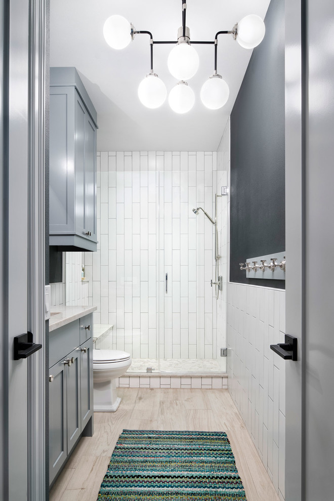 Inspiration for a mid-sized contemporary bathroom in Austin with recessed-panel cabinets, grey cabinets, a one-piece toilet, white tile, ceramic tile, grey walls, porcelain floors, quartzite benchtops and a hinged shower door.