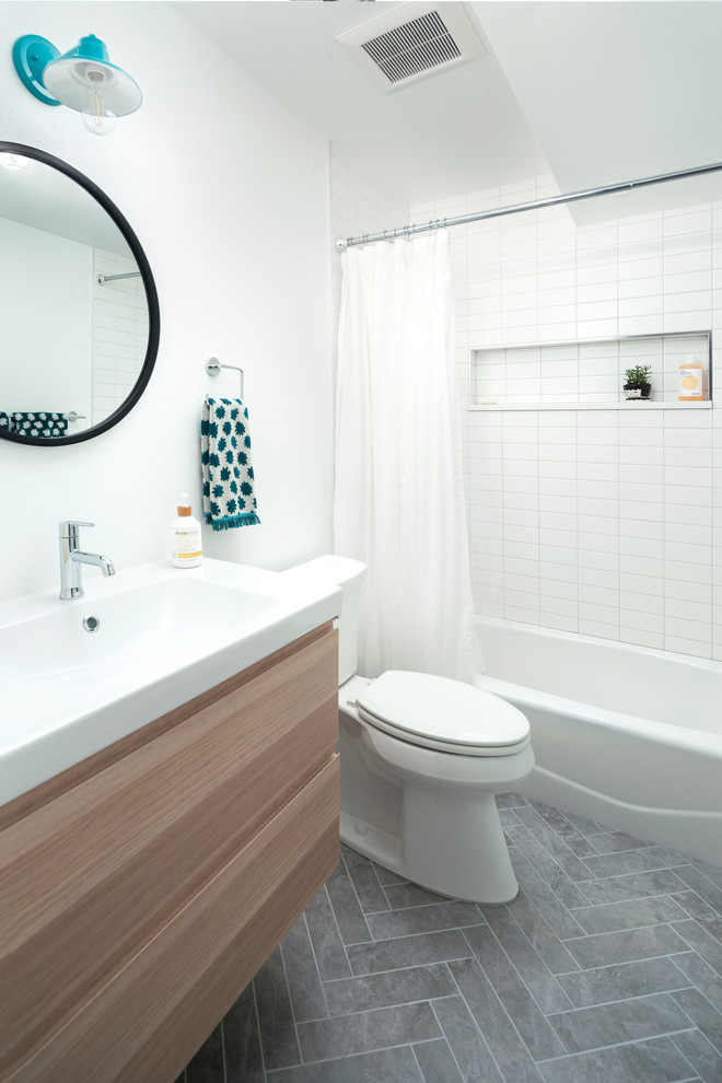 Photo of a country bathroom in Denver with flat-panel cabinets, light wood cabinets, an alcove tub, a shower/bathtub combo, white tile, ceramic tile, white walls, porcelain floors, grey floor and a shower curtain.