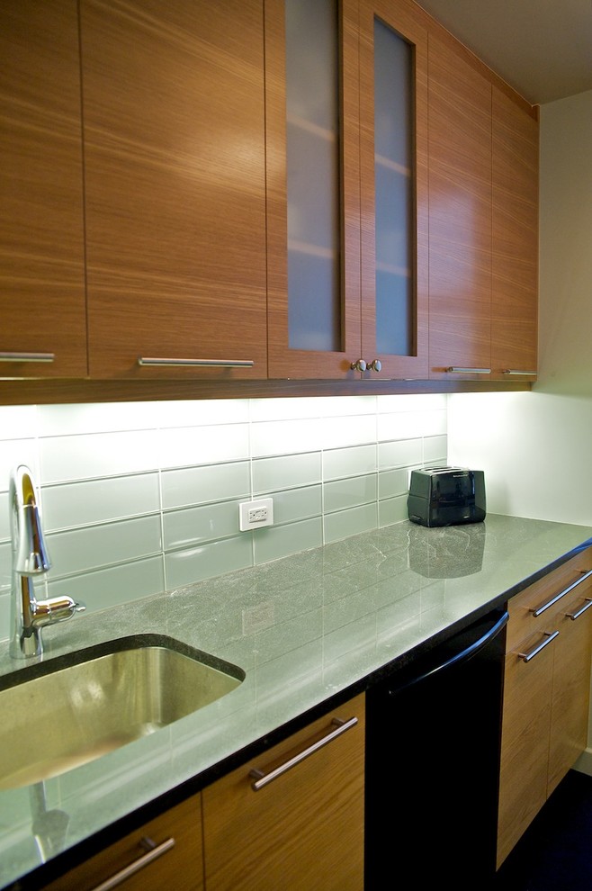 This is an example of a mid-sized contemporary galley eat-in kitchen in New York with a single-bowl sink, flat-panel cabinets, medium wood cabinets, green splashback, glass tile splashback, no island, black appliances and granite benchtops.