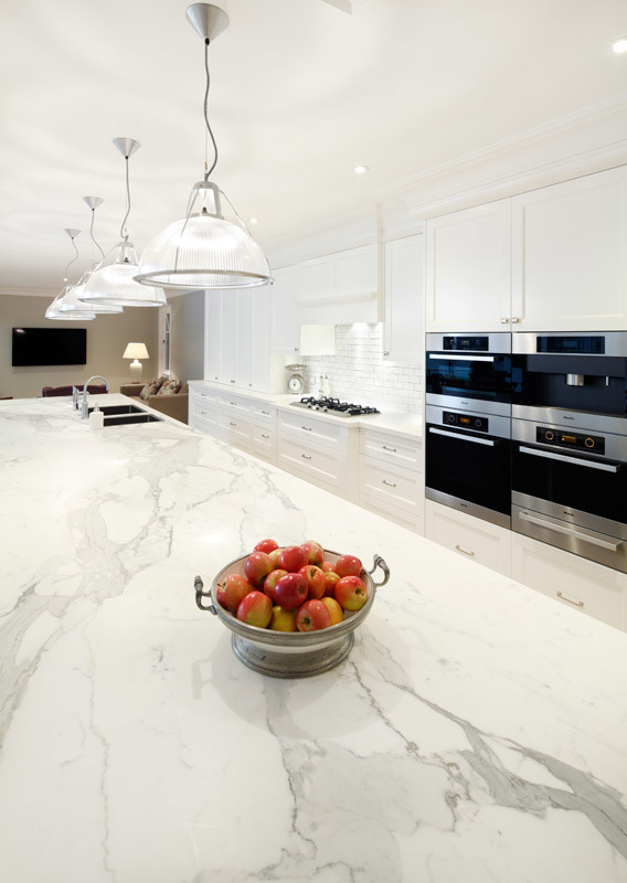 Inspiration for an expansive traditional galley eat-in kitchen in Sydney with a drop-in sink, shaker cabinets, white cabinets, marble benchtops, white splashback, brick splashback, stainless steel appliances, ceramic floors, with island and beige floor.