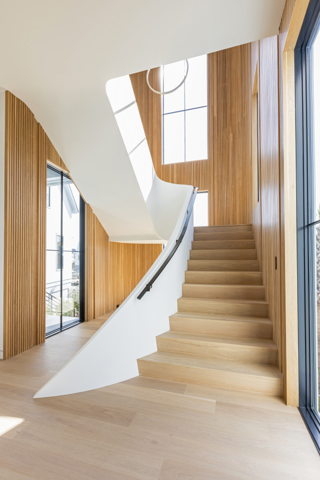 Modelo de escalera curva moderna grande con escalones de madera, contrahuellas de madera, barandilla de varios materiales y madera