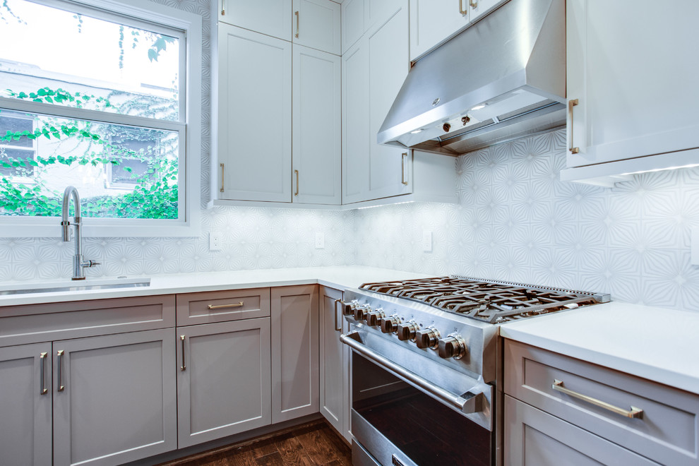 Inspiration for a large transitional l-shaped medium tone wood floor and brown floor eat-in kitchen remodel in DC Metro with an undermount sink, shaker cabinets, white cabinets, solid surface countertops, white backsplash, ceramic backsplash, stainless steel appliances, an island and white countertops