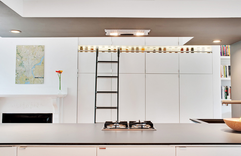 Photo of a contemporary kitchen in Boston with an undermount sink, flat-panel cabinets, white cabinets, solid surface benchtops, grey splashback and stainless steel appliances.