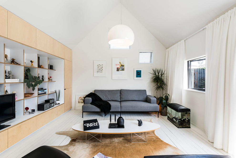 Photo of a small contemporary open concept living room in Christchurch with white walls, painted wood floors and a built-in media wall.