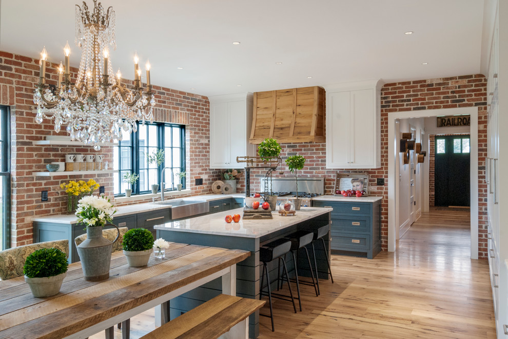 Design ideas for a mid-sized country eat-in kitchen in Cleveland with a farmhouse sink, shaker cabinets, blue cabinets, marble benchtops, multi-coloured splashback, stainless steel appliances, light hardwood floors and with island.