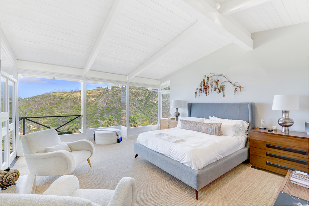 This is an example of a beach style master bedroom in Orange County with grey walls, carpet and beige floor.