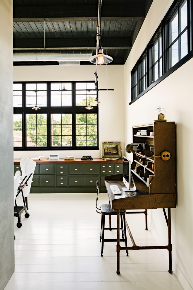 This is an example of an industrial home office in Portland with white walls, painted wood floors, a freestanding desk and white floor.