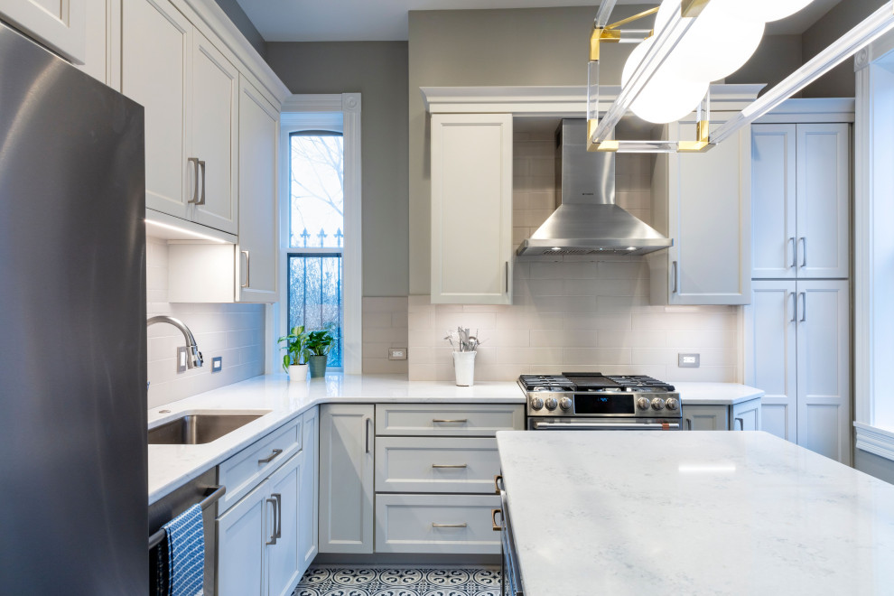 Transitional porcelain tile kitchen photo with white backsplash, ceramic backsplash, stainless steel appliances, an island and white countertops