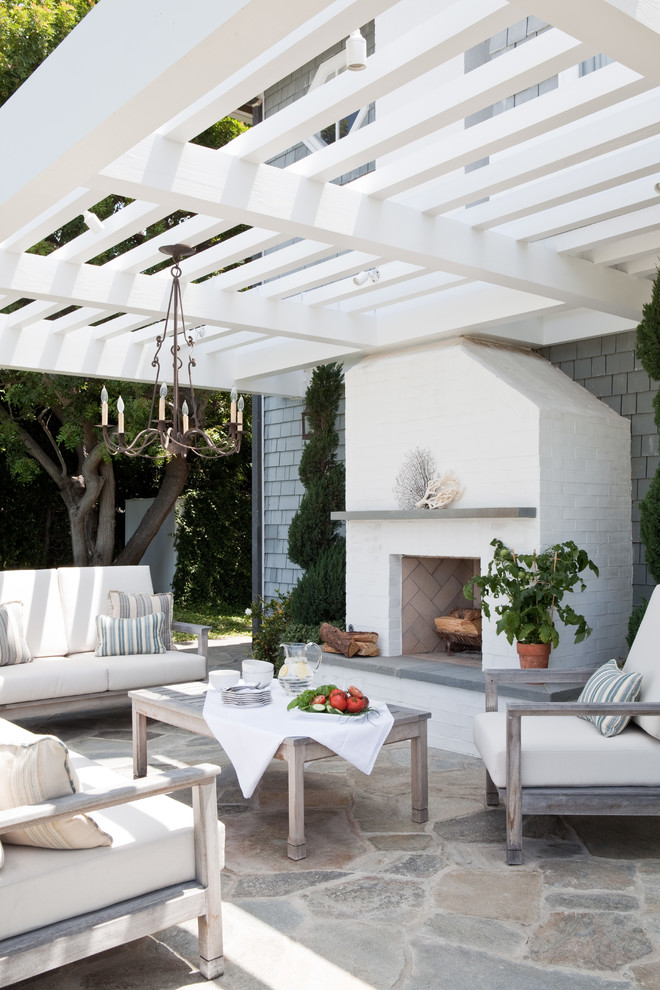 This is an example of a beach style patio in Los Angeles with natural stone pavers and a pergola.
