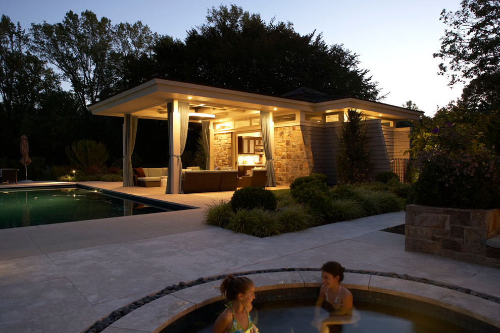 This is an example of an expansive modern backyard rectangular lap pool in New York with a pool house and natural stone pavers.
