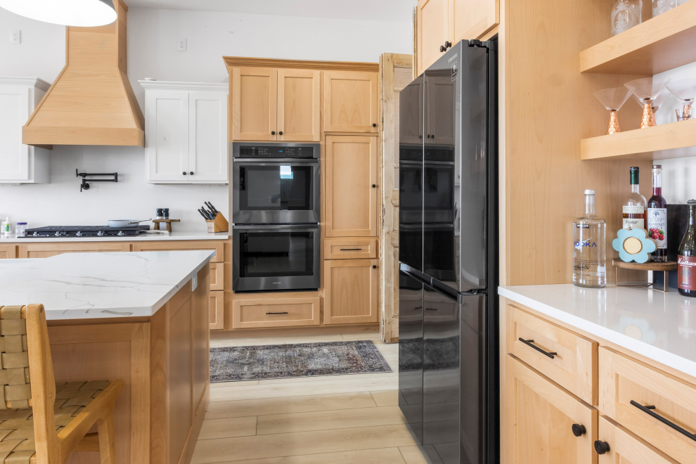 Mid-sized modern u-shaped eat-in kitchen in St Louis with a drop-in sink, beaded inset cabinets, beige cabinets, marble benchtops, white splashback, black appliances, vinyl floors, with island, beige floor, white benchtop and vaulted.