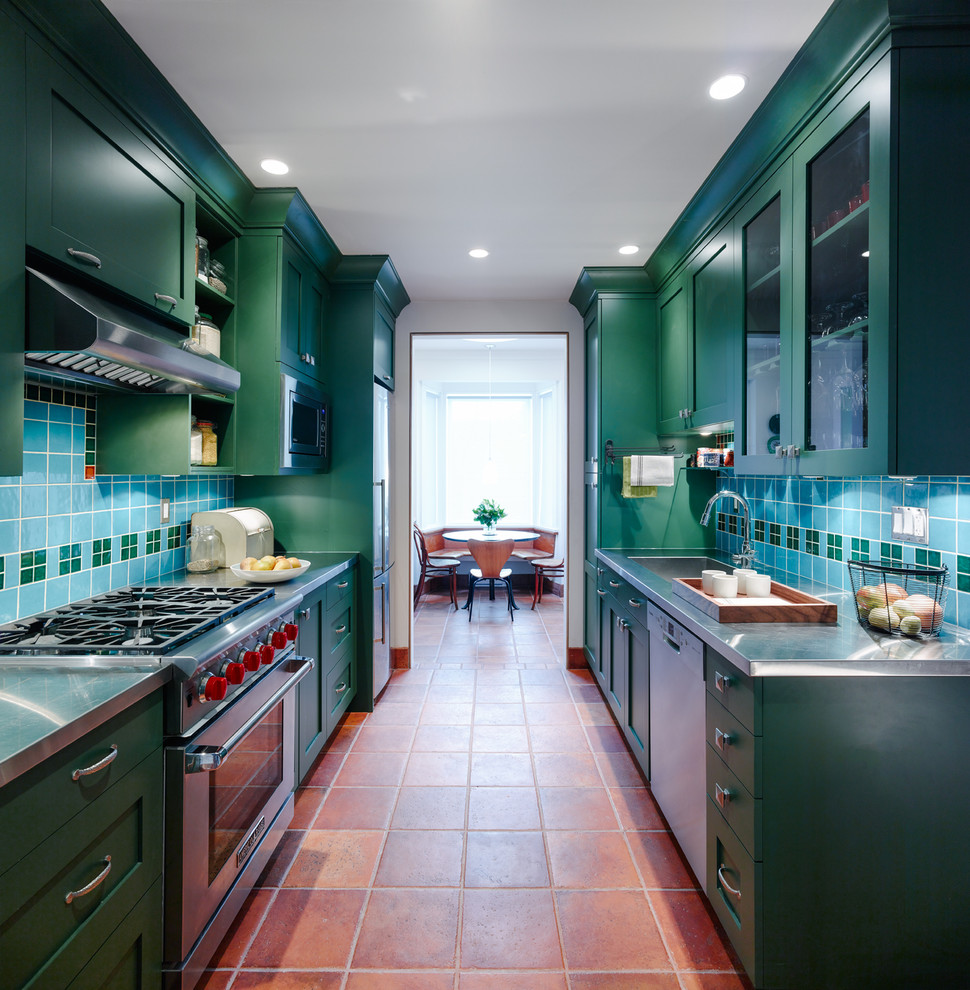 Photo of a traditional galley kitchen in Vancouver with an integrated sink, shaker cabinets, green cabinets, stainless steel benchtops, multi-coloured splashback, ceramic splashback, stainless steel appliances, terra-cotta floors and no island.