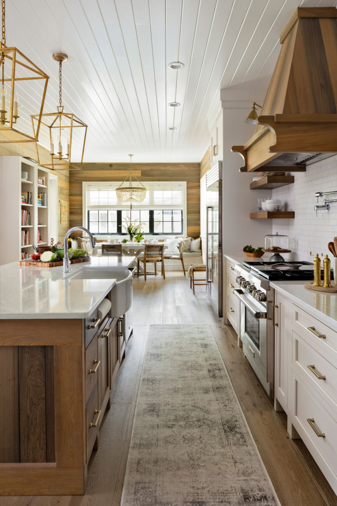 Example of a large trendy galley medium tone wood floor, brown floor and shiplap ceiling eat-in kitchen design in Orlando with a drop-in sink, beaded inset cabinets, white cabinets, granite countertops, white backsplash, stone tile backsplash, stainless steel appliances, an island and white countertops