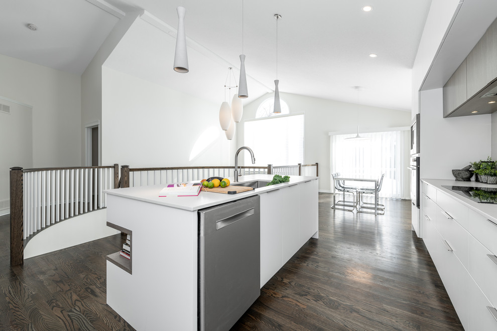 Photo of a mid-sized contemporary u-shaped eat-in kitchen in Ottawa with an undermount sink, white cabinets, stainless steel appliances, with island, brown floor, flat-panel cabinets, quartz benchtops, white splashback, porcelain splashback, dark hardwood floors and grey benchtop.