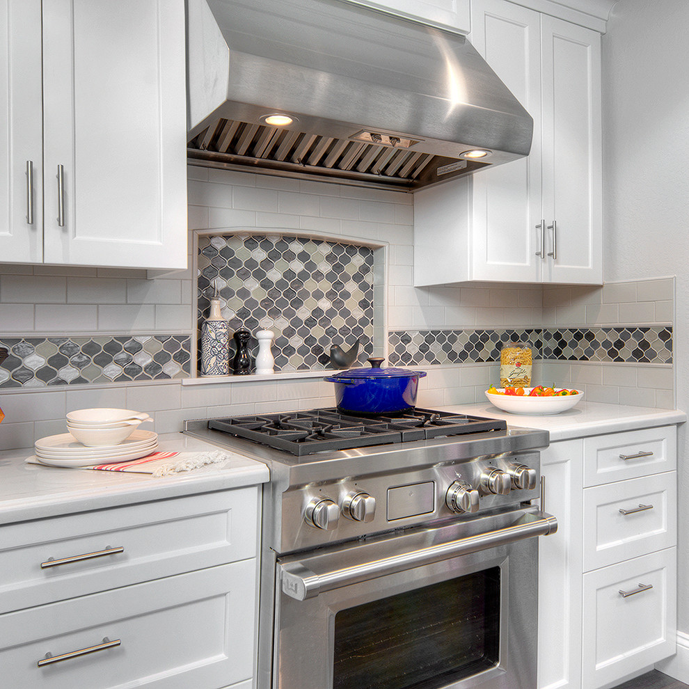 Photo of a mid-sized transitional galley eat-in kitchen in San Francisco with an undermount sink, shaker cabinets, white cabinets, quartz benchtops, multi-coloured splashback, mosaic tile splashback, stainless steel appliances, vinyl floors, no island, brown floor and white benchtop.