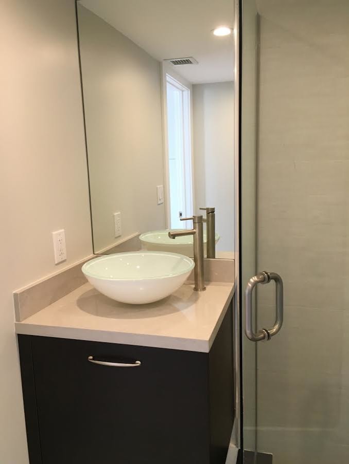 This is an example of a mid-sized contemporary master bathroom in Miami with flat-panel cabinets, dark wood cabinets, a corner shower, beige tile, white walls, laminate floors, an undermount sink and engineered quartz benchtops.