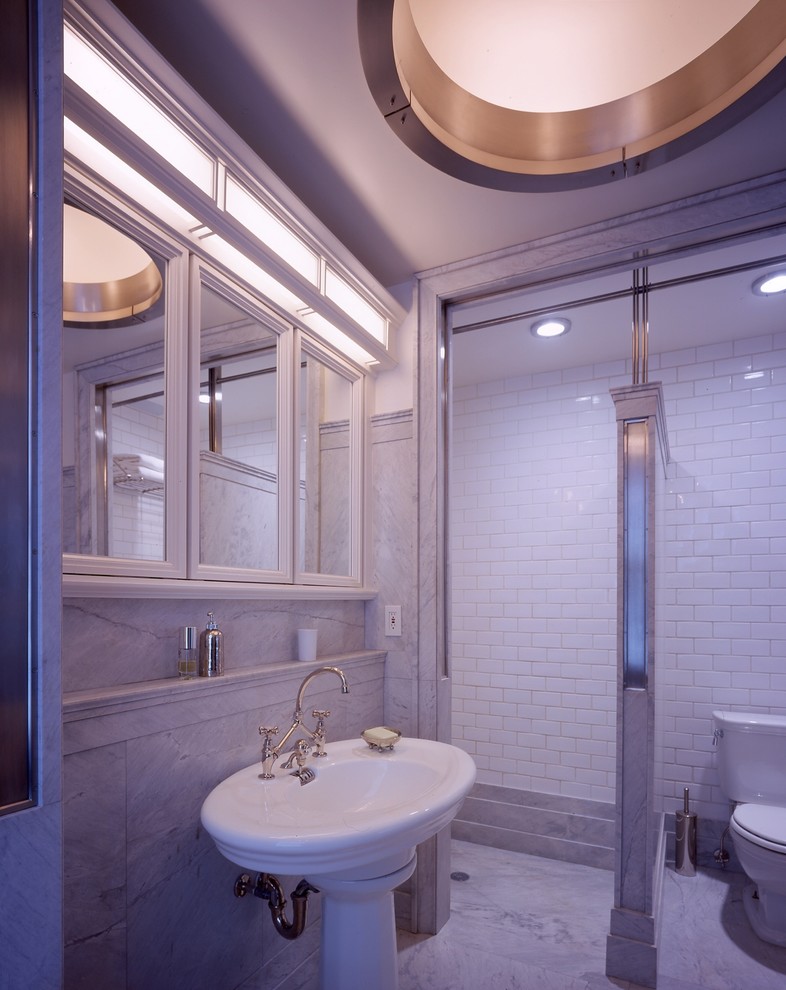 Photo of a mid-sized transitional master bathroom in New York with a pedestal sink, glass-front cabinets, white cabinets, marble benchtops, a drop-in tub, a curbless shower, a two-piece toilet, white tile, subway tile and marble floors.