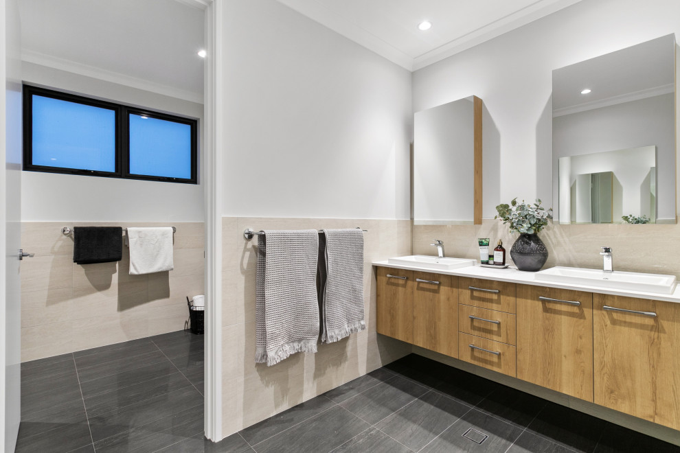 Photo of a contemporary bathroom in Perth with flat-panel cabinets, medium wood cabinets, beige tile, white walls, a drop-in sink, grey floor, white benchtops, an enclosed toilet, a double vanity and a floating vanity.