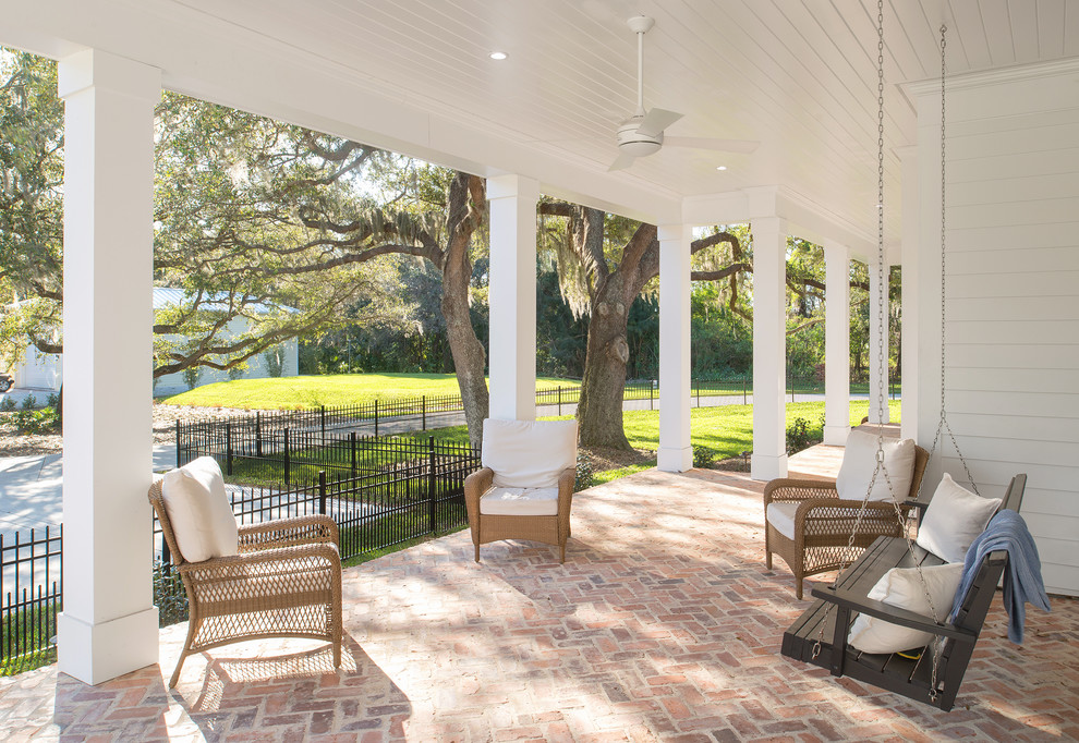 Photo of a large transitional front yard verandah in Tampa with brick pavers and a roof extension.