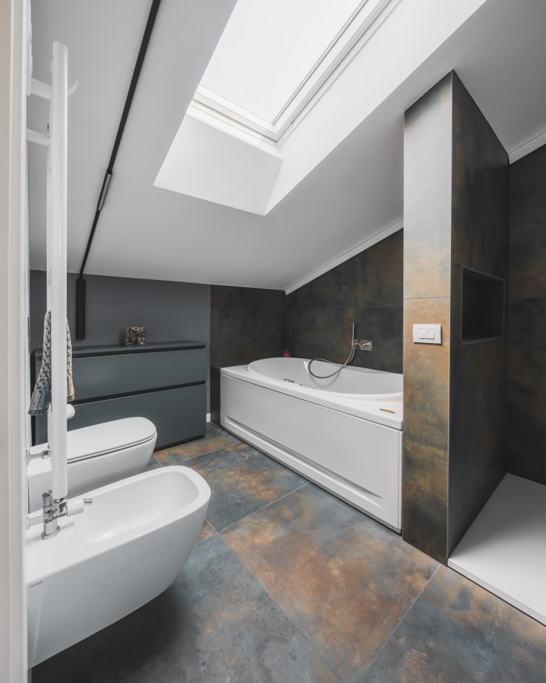 This is an example of a large industrial 3/4 bathroom in Milan with flat-panel cabinets, grey cabinets, an alcove tub, a double shower, a two-piece toilet, multi-coloured tile, porcelain tile, multi-coloured walls, porcelain floors, a vessel sink, wood benchtops, multi-coloured floor, an open shower, beige benchtops and a single vanity.