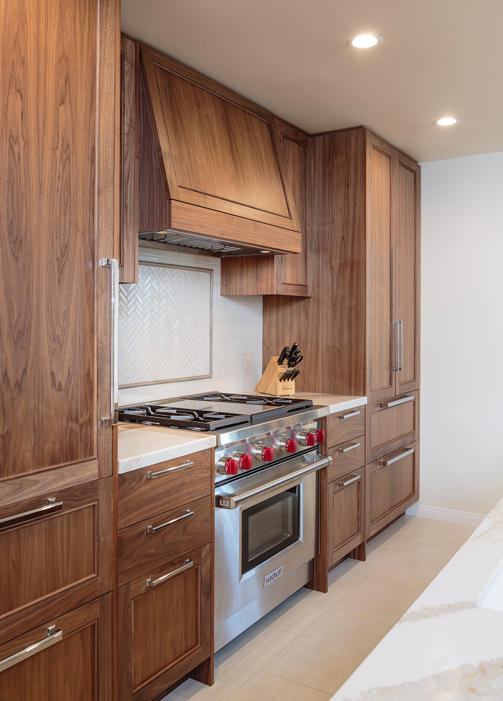 Inspiration for a mid-sized transitional beige floor and limestone floor open concept kitchen remodel in Los Angeles with an undermount sink, recessed-panel cabinets, medium tone wood cabinets, quartz countertops, white backsplash, ceramic backsplash, stainless steel appliances, an island and white countertops
