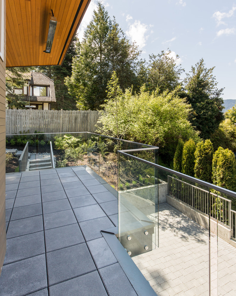 Design ideas for a large modern balcony in Vancouver with an awning and glass railing.