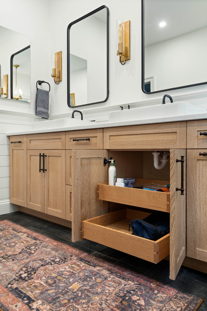 This is an example of a mid-sized industrial master bathroom in Other with shaker cabinets, light wood cabinets, a freestanding tub, a curbless shower, a two-piece toilet, white tile, porcelain tile, white walls, porcelain floors, a vessel sink, engineered quartz benchtops, black floor, a hinged shower door, white benchtops, a niche, a double vanity, a built-in vanity and planked wall panelling.