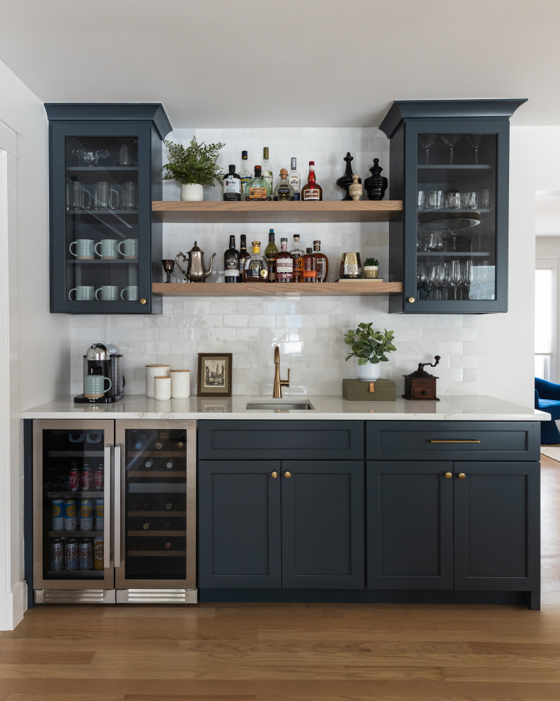 Inspiration for a mid-sized transitional single-wall light wood floor wet bar remodel in Chicago with an undermount sink, shaker cabinets, blue cabinets, quartz countertops, white backsplash, marble backsplash and white countertops