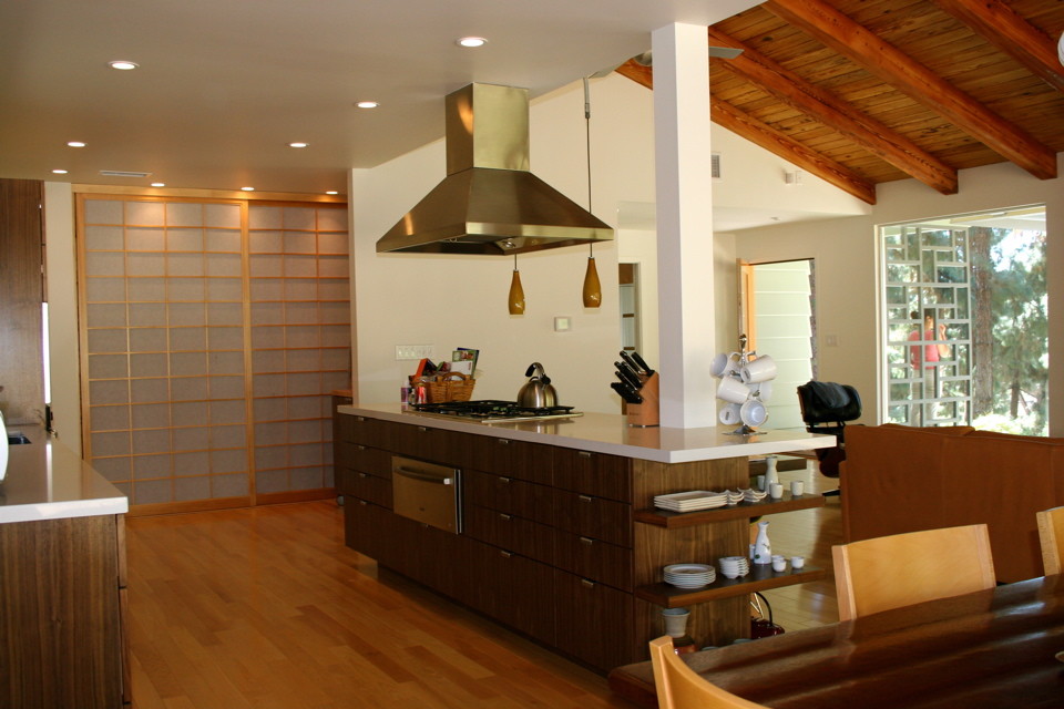This is an example of a mid-sized asian single-wall open plan kitchen in Los Angeles with flat-panel cabinets, medium wood cabinets, stainless steel appliances, with island and light hardwood floors.