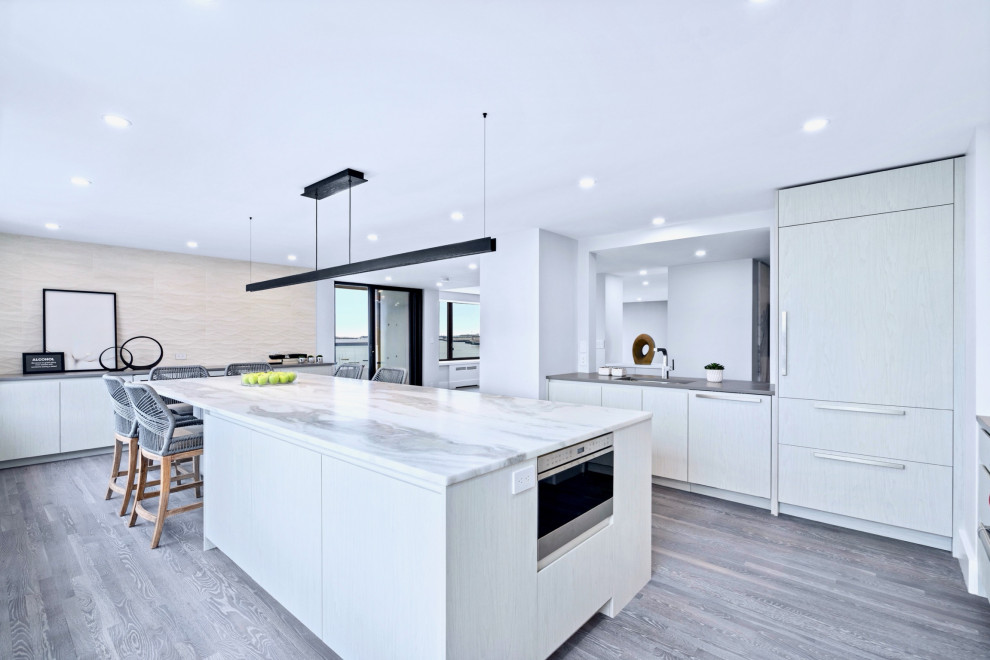 Large trendy light wood floor and gray floor eat-in kitchen photo in Boston with an undermount sink, flat-panel cabinets, white cabinets, quartzite countertops, gray backsplash, stone slab backsplash, stainless steel appliances, an island and gray countertops