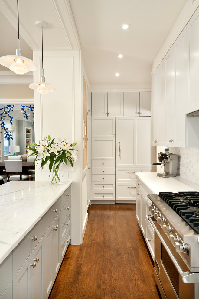 Inspiration for a small transitional u-shaped open plan kitchen in New York with grey splashback, panelled appliances, an undermount sink, marble benchtops, stone tile splashback, medium hardwood floors, a peninsula, shaker cabinets, white cabinets and brown floor.
