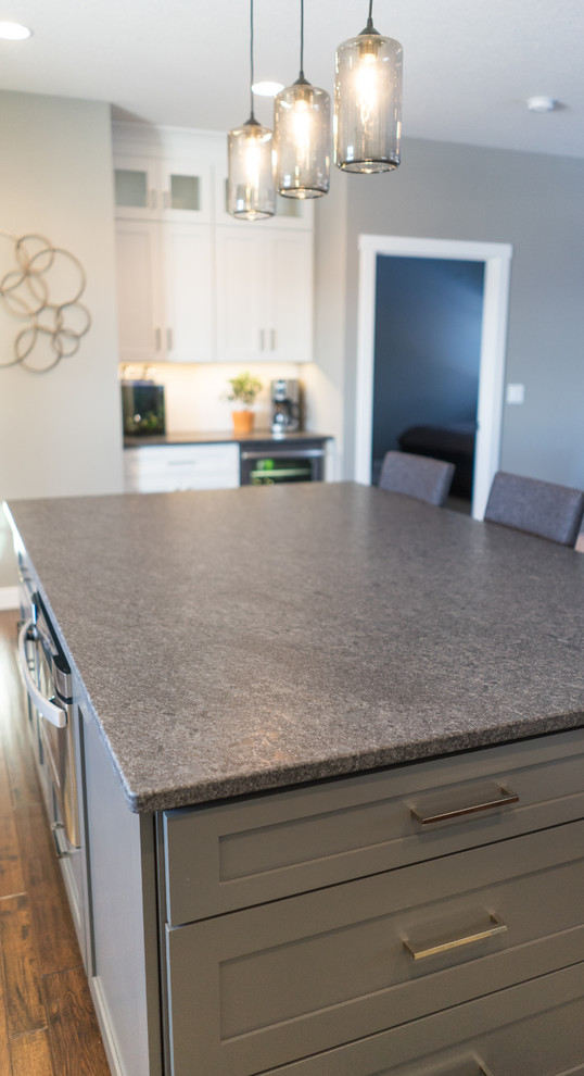 Inspiration for a large transitional u-shaped eat-in kitchen remodel with a farmhouse sink, flat-panel cabinets, white cabinets, granite countertops, white backsplash, ceramic backsplash, stainless steel appliances and an island