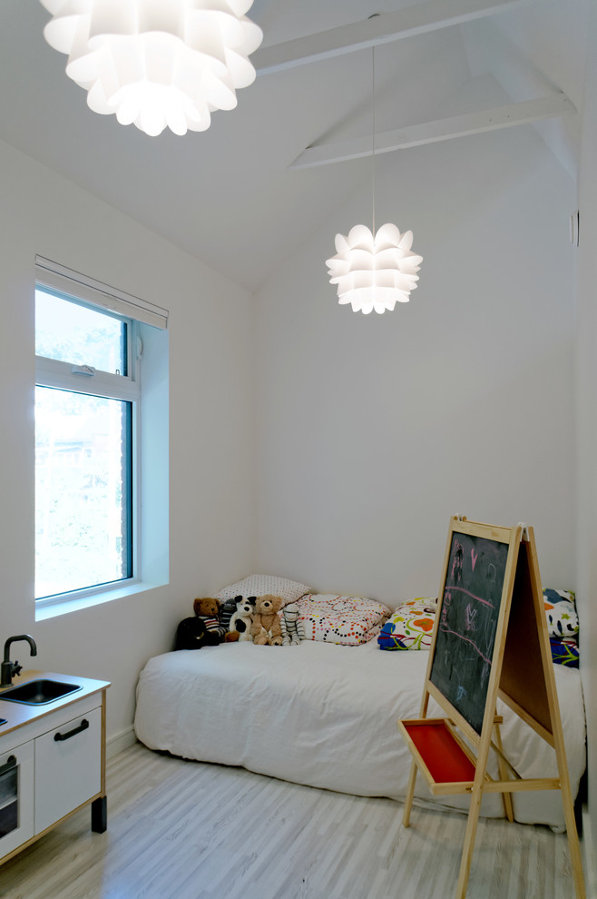 Design ideas for a small scandinavian gender-neutral kids' playroom for kids 4-10 years old in Toronto with white walls and light hardwood floors.