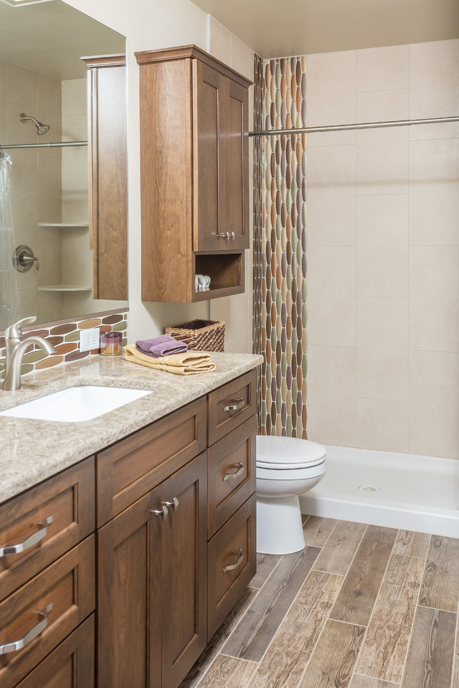Photo of a small transitional master bathroom in Other with recessed-panel cabinets, dark wood cabinets, an alcove shower, a one-piece toilet, beige tile, glass tile, beige walls, porcelain floors, an undermount sink, engineered quartz benchtops, grey floor and a shower curtain.