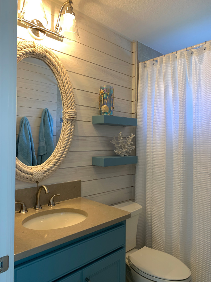 This is an example of a tropical bathroom in Orlando with recessed-panel cabinets, blue cabinets, an undermount sink, engineered quartz benchtops and beige benchtops.