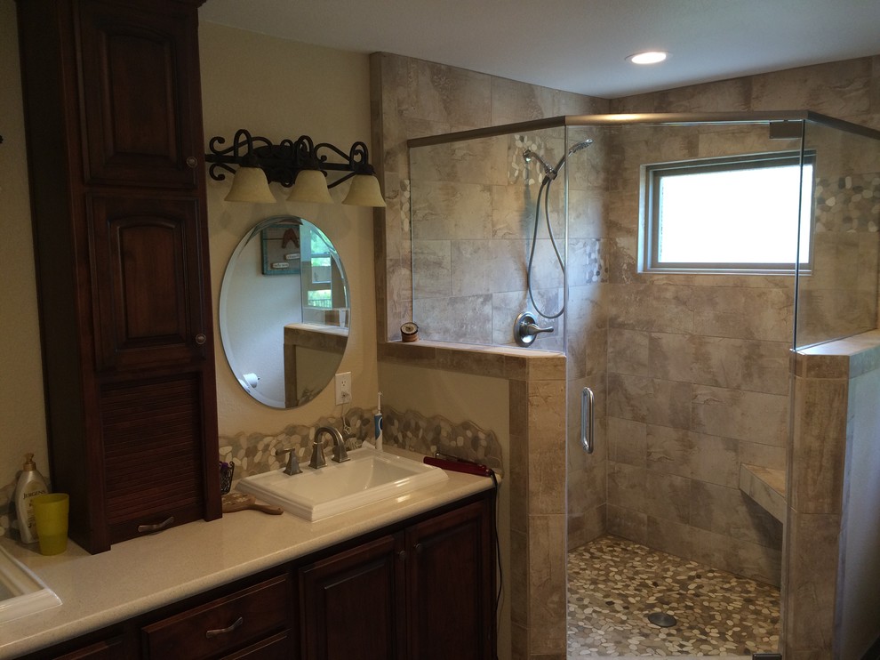Inspiration for a mid-sized traditional 3/4 bathroom in Sacramento with a drop-in sink, raised-panel cabinets, dark wood cabinets, a corner shower, beige tile, porcelain tile, yellow walls and pebble tile floors.