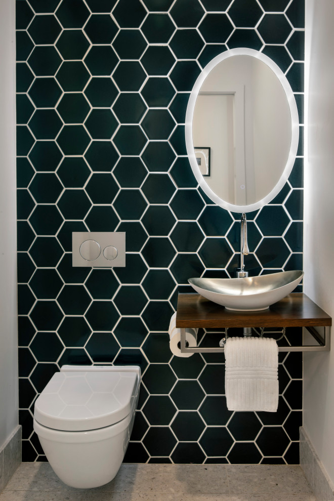 Foto de aseo moderno con sanitario de pared, baldosas y/o azulejos azules, lavabo sobreencimera y encimera de madera