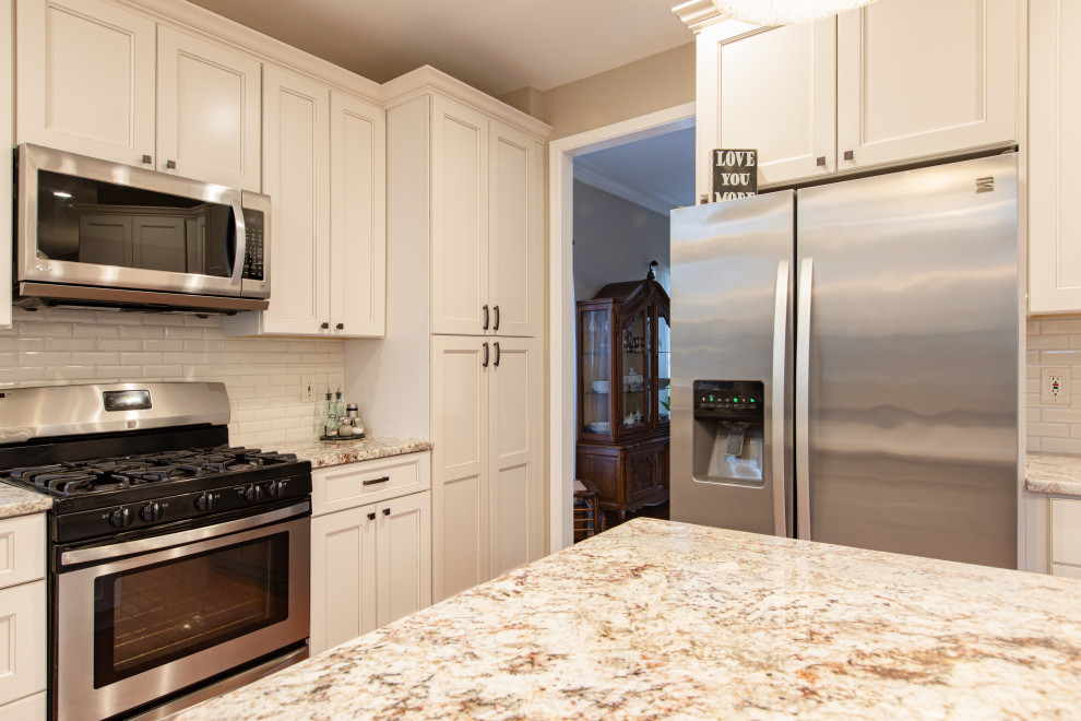 Photo of a large traditional u-shaped eat-in kitchen in DC Metro with an undermount sink, raised-panel cabinets, beige cabinets, granite benchtops, beige splashback, porcelain splashback, stainless steel appliances, medium hardwood floors, with island, orange floor and multi-coloured benchtop.