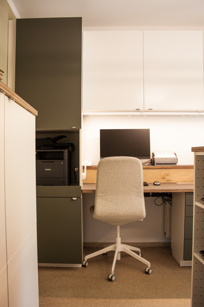 Immagine di un piccolo ufficio nordico con pareti verdi, pavimento in sughero, nessun camino, scrivania incassata, pavimento marrone, soffitto in carta da parati e carta da parati