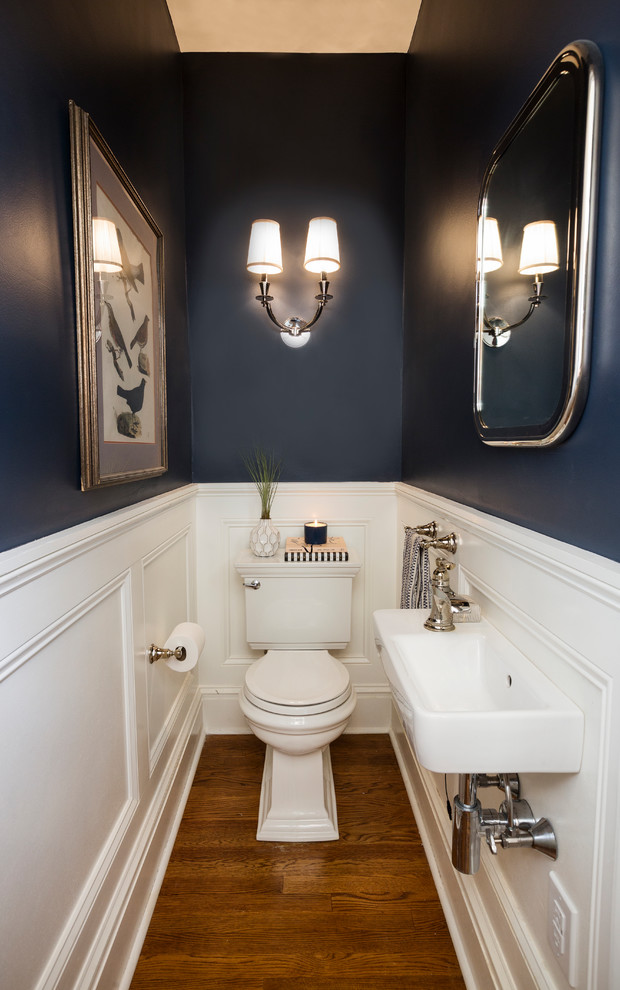 Photo of a small transitional powder room in Philadelphia with a two-piece toilet, blue walls, medium hardwood floors, a wall-mount sink and brown floor.