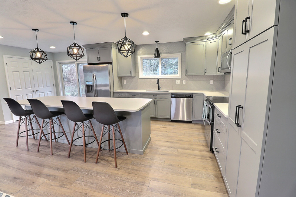 Design ideas for a mid-sized transitional l-shaped open plan kitchen in Other with an undermount sink, shaker cabinets, grey cabinets, quartz benchtops, white splashback, porcelain splashback, stainless steel appliances, vinyl floors, with island, beige floor and white benchtop.