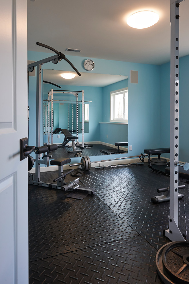 This is an example of a mid-sized transitional home weight room in Grand Rapids with blue walls and black floor.