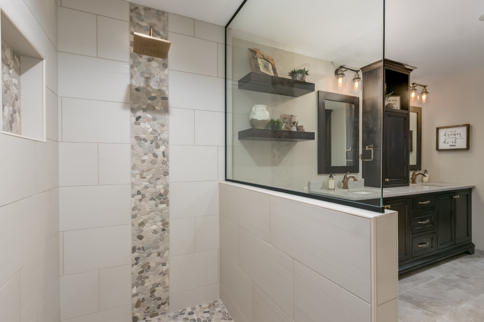 This is an example of a mid-sized beach style master bathroom in Minneapolis with flat-panel cabinets, dark wood cabinets, a drop-in tub, an open shower, a one-piece toilet, beige tile, ceramic tile, beige walls, laminate floors, a drop-in sink, marble benchtops, beige floor, an open shower, multi-coloured benchtops, a double vanity and a floating vanity.
