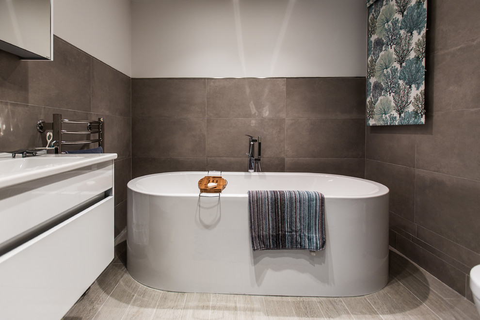 This is an example of a mid-sized contemporary master bathroom in Other with open cabinets, white cabinets, solid surface benchtops, a freestanding tub, a shower/bathtub combo, gray tile, cement tile, white walls, a console sink and a one-piece toilet.