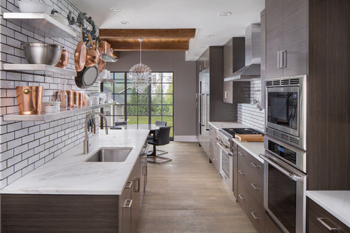 Modern galley kitchen with flat-panel gray kitchen cabinets, white subway tile backsplash, and stainless steel appliances